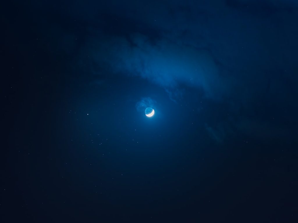 A wide view of a star-filled night sky with visible planets and glowing celestial light